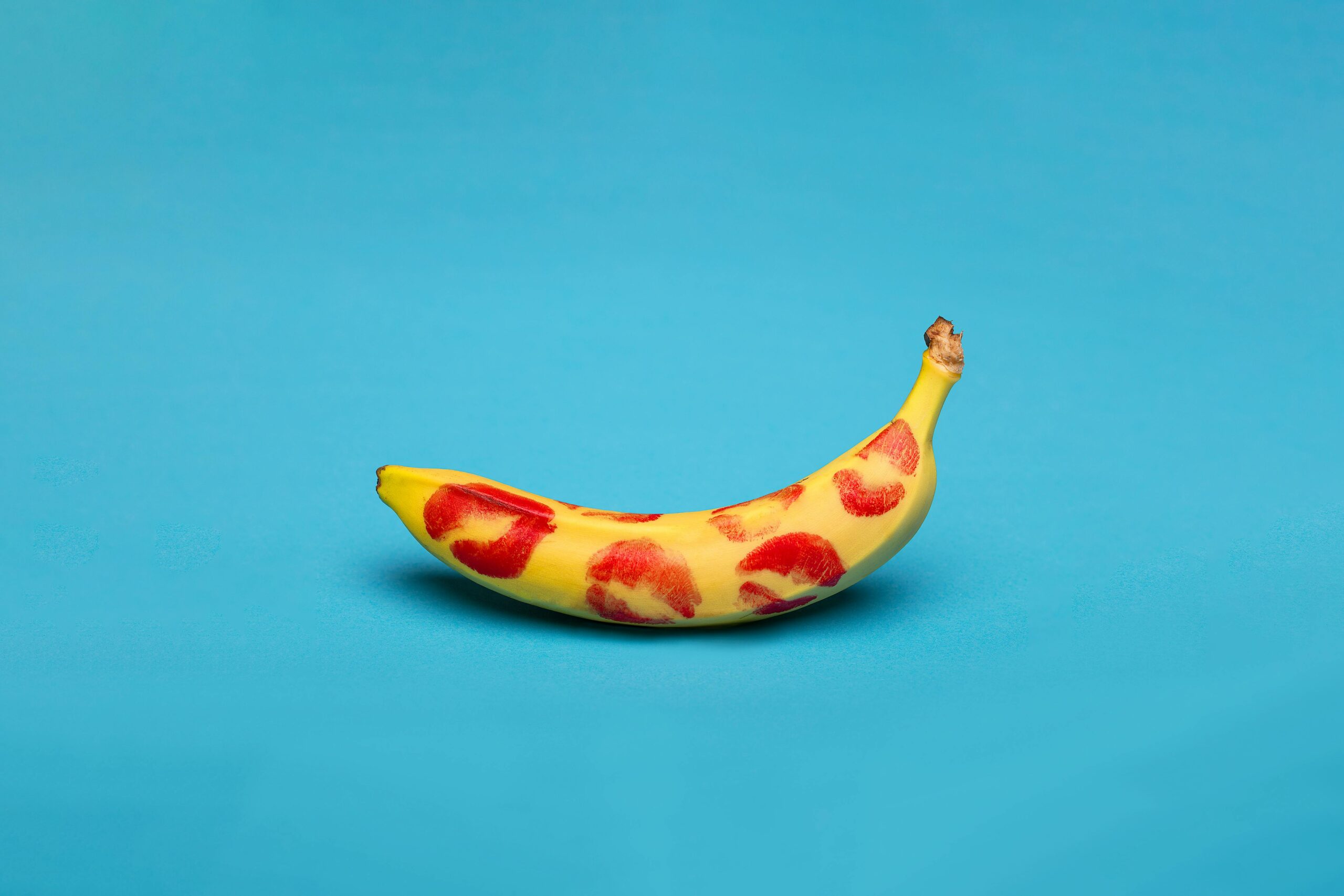 Banane mit Kussabdrücken vor blauem Hintergrund.