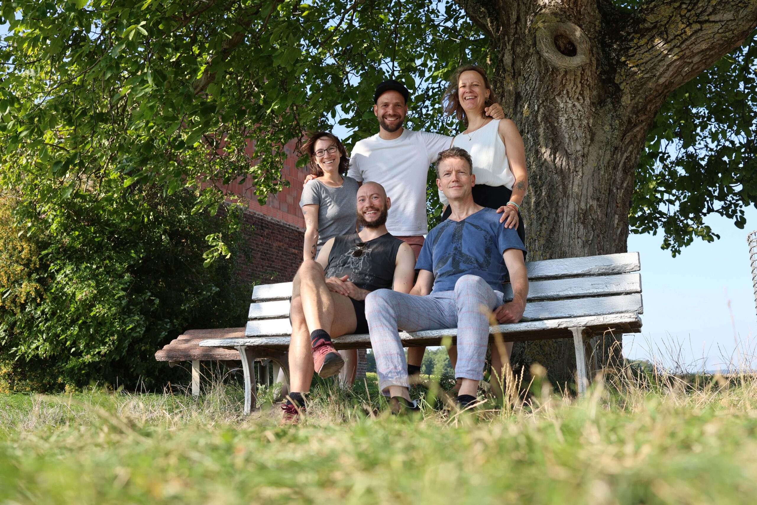 Fünf Menschen von der Supportive Sexwork Collective um eine Bank unter einem Baum