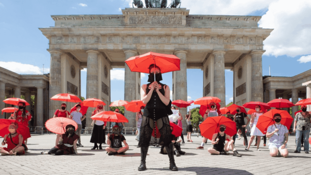 Anonyme Sexarbeitende mit roten Regenschirmen vor dem Brandenburger Tor – Sexarbeitsaktivismus