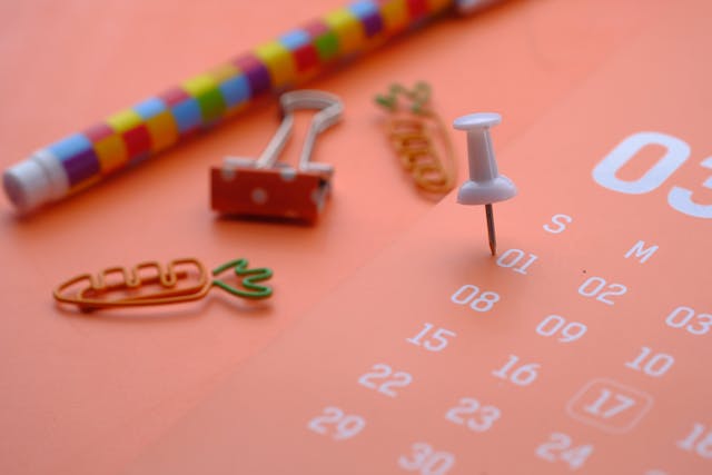 Termin Kalender auf pastell Untergrund mit Stecknadel und Klammern
