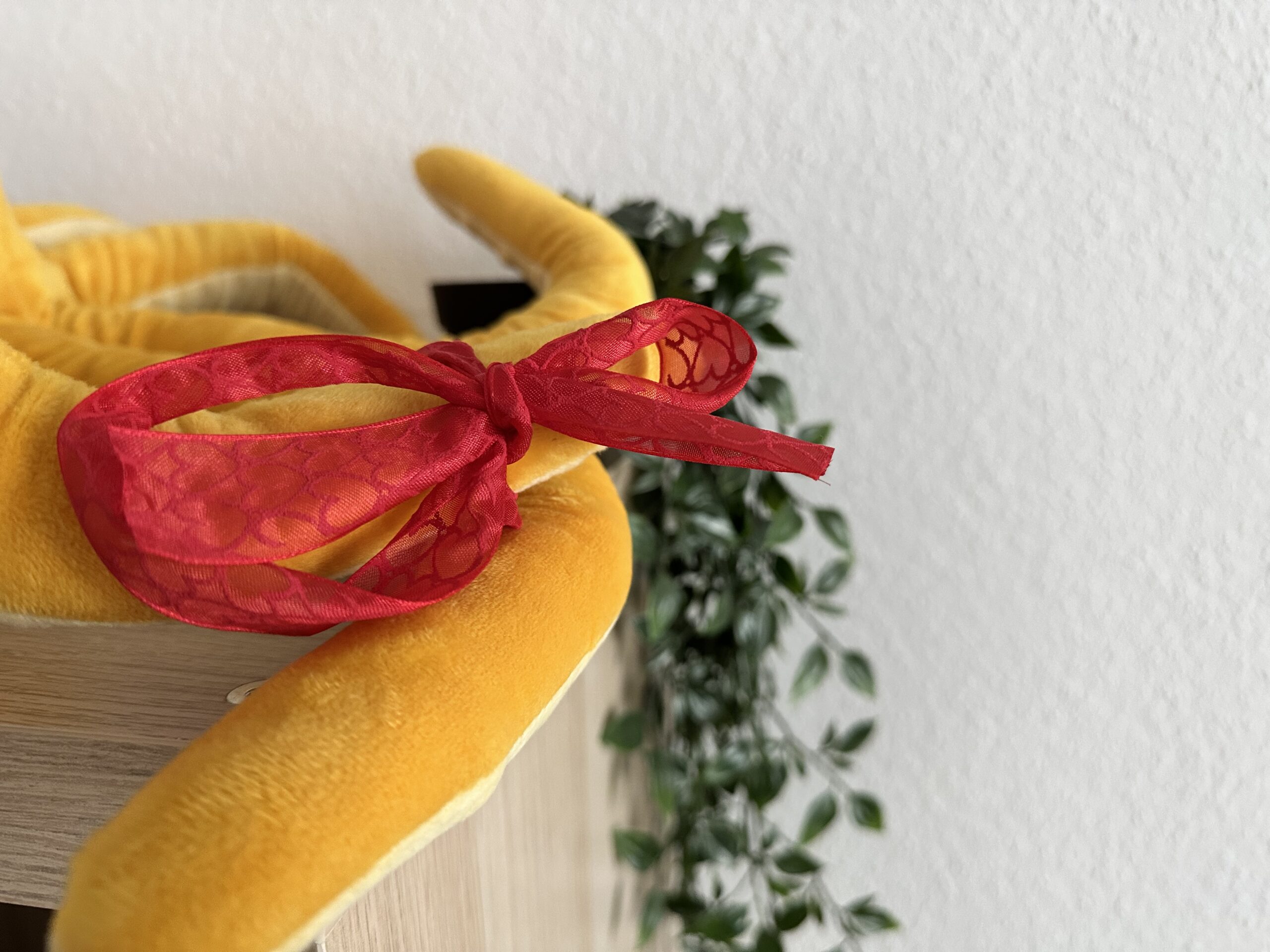 Schleife quer 1 Rote Schleife am Arm eines Plüsch-Oktopusses auf einem Regal.